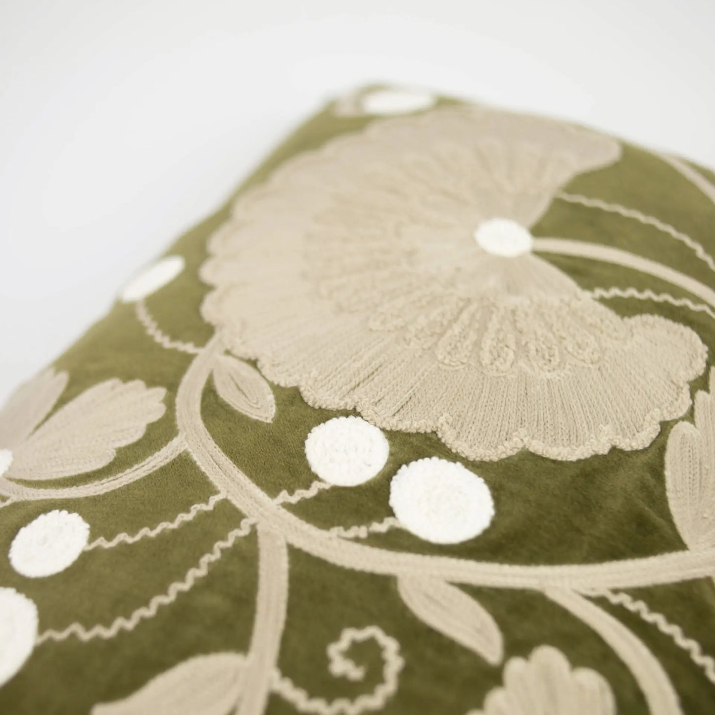 Coussin rectangulaire en velours vert kaki avec des broderies beige, à motif floral.