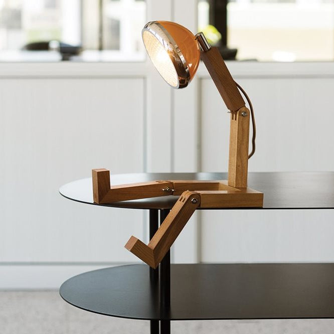 Lampe à poser en forme de bonhomme articulé avec un phare à la place de la tête, coloris orange.