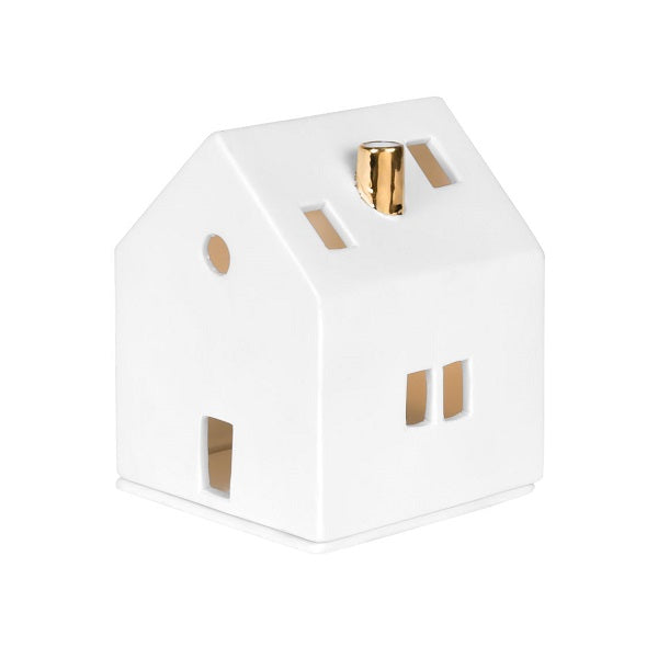 Photophore en porcelaine blanche en forme de maison avec une cheminée dorée, allumée.