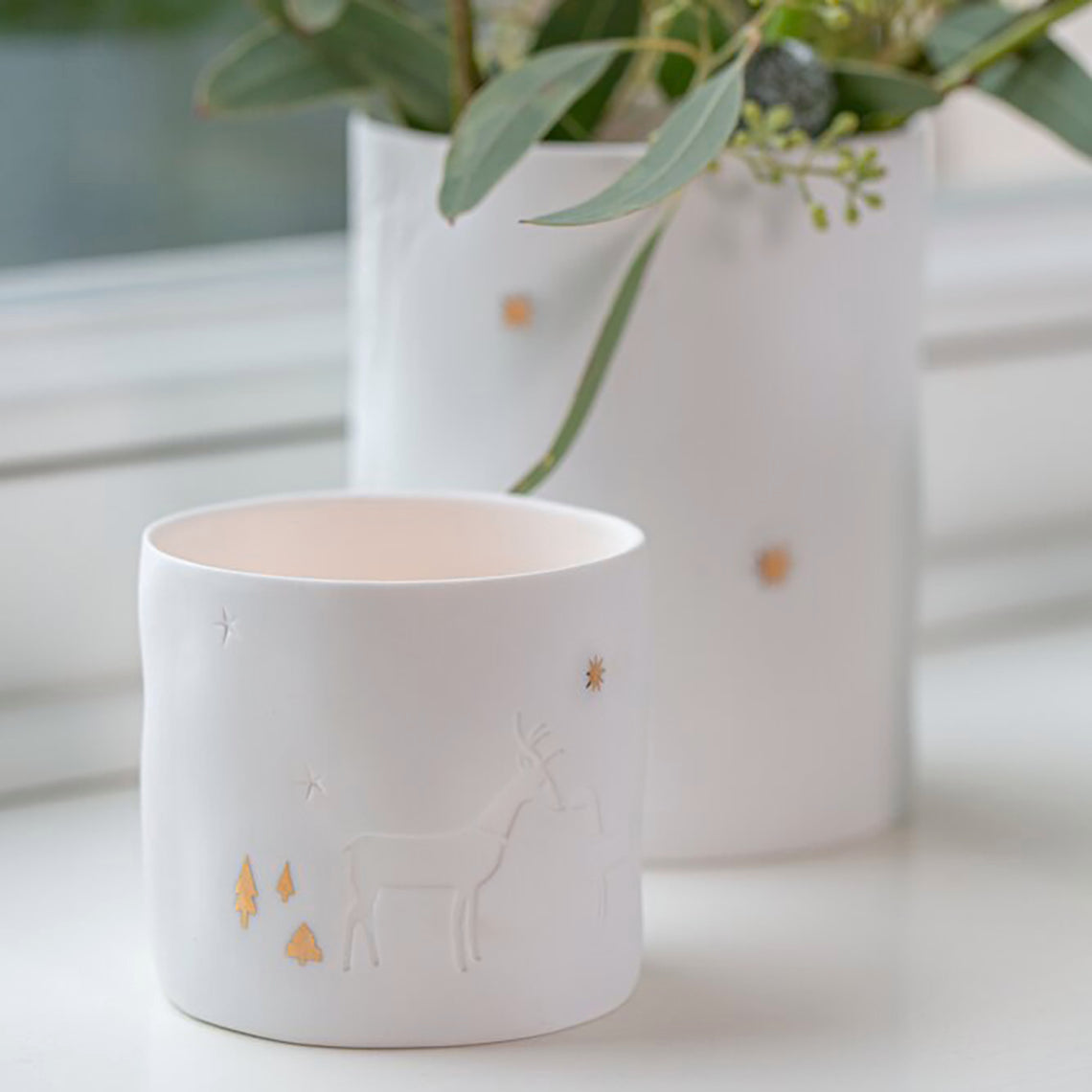 Photophores ronds en porcelaine avec détails gaufrés et dorés.