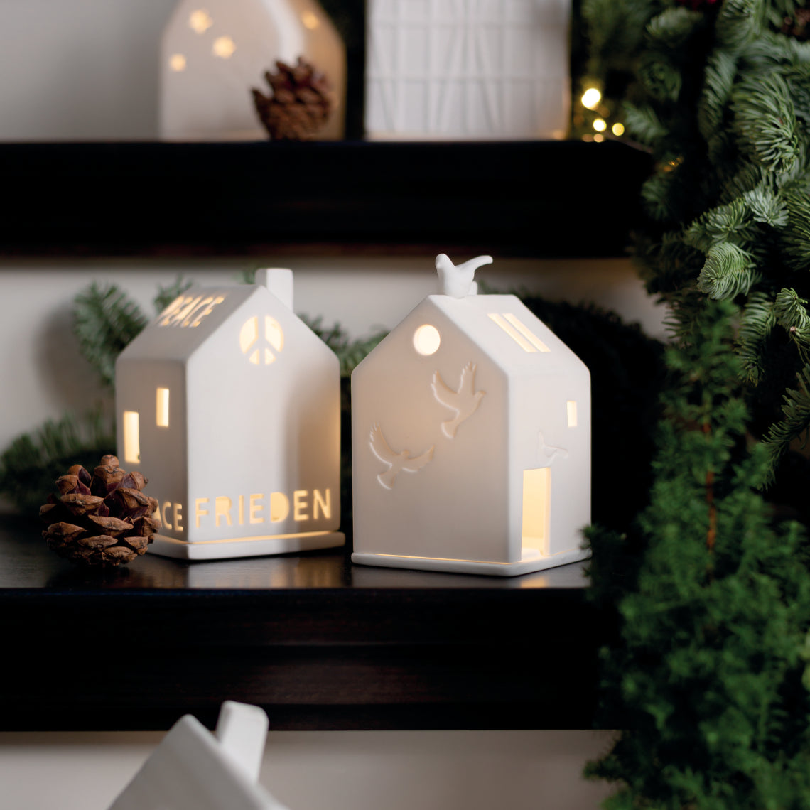 Photophore en porcelaine blanche en forme de maison avec écrit le mot "Paix" en plusieurs langues.