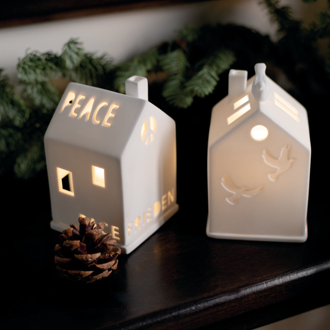 Photophore en porcelaine blanche en forme de maison avec écrit le mot "Paix" en plusieurs langues.