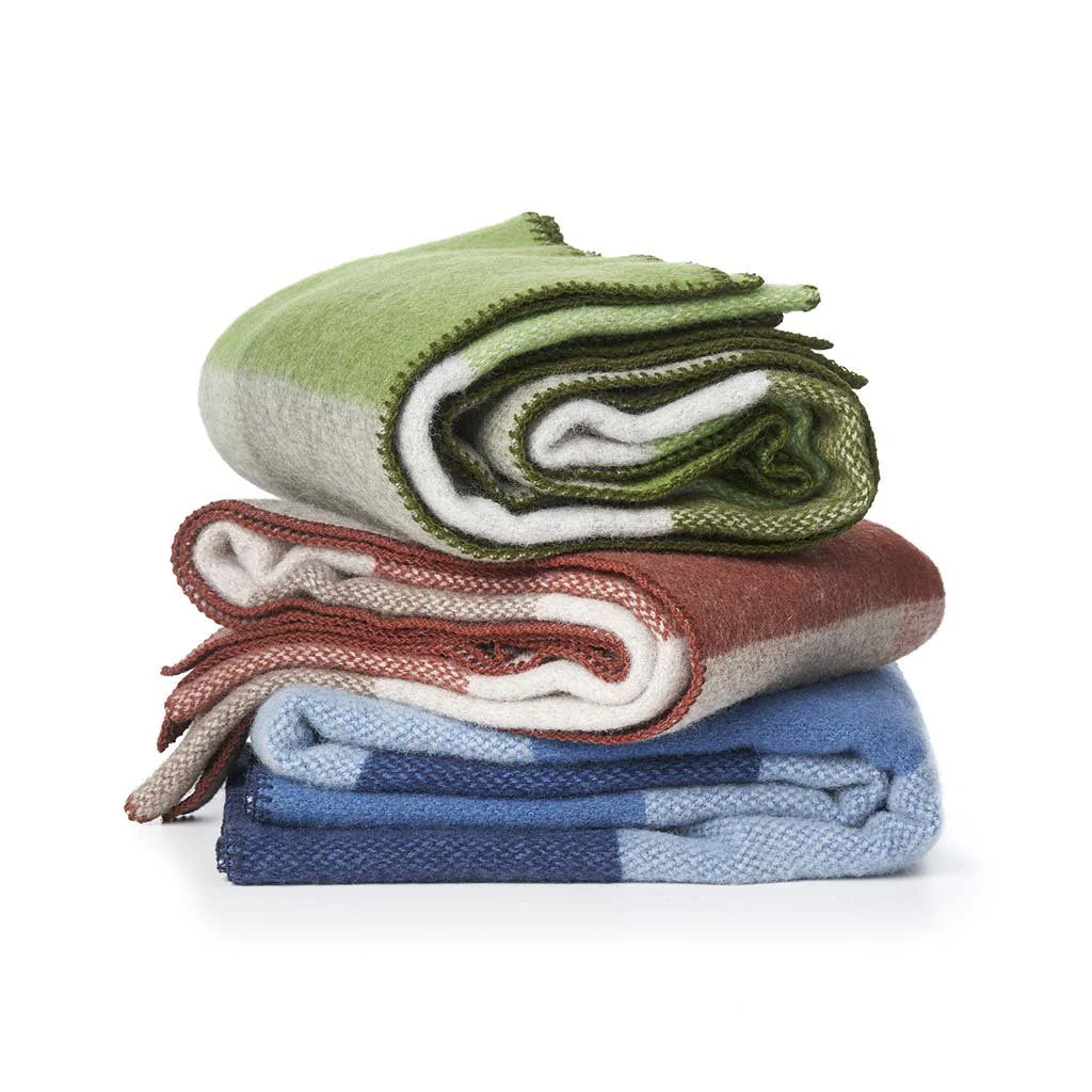 Pile de plaids en laine d'agneaux à grands carreaux colorés.