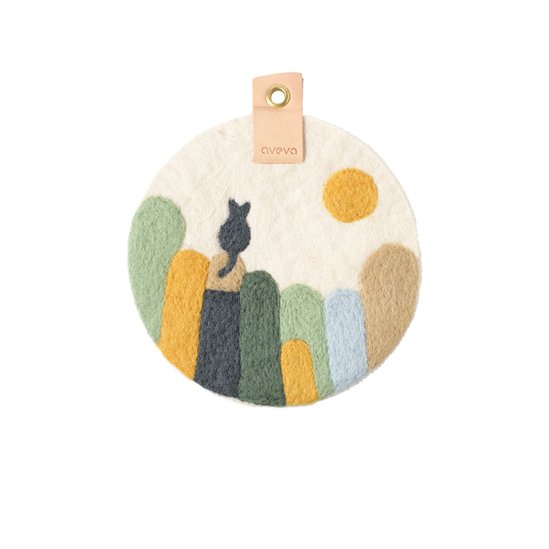 Tableau rond en laine avec un chat noir sur une palissade, coloris vert, bleu jaune et blanc.