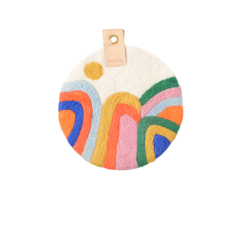 Tableau rond en laine avec des montagnes multicolores : bleu, orange, jaune, rose, vert.