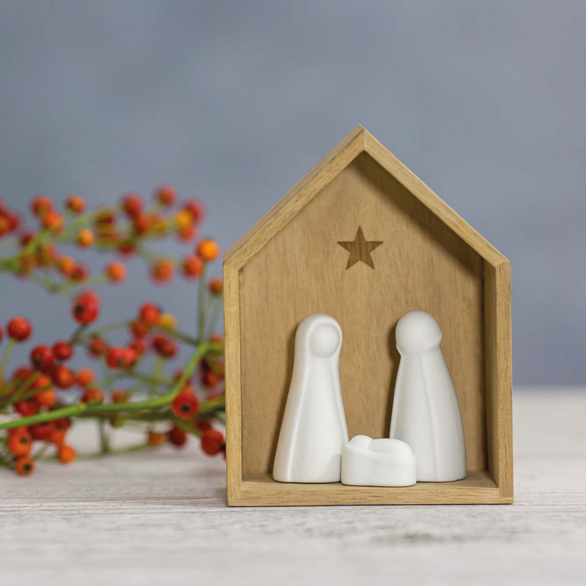Petite crèche en bois abritant trois figurines en porcelaine.