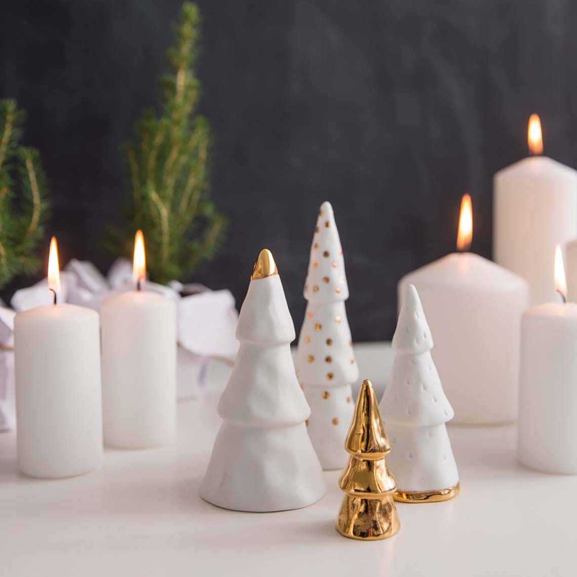 Lot de 4 sapins décoratifs de différentes tailles, en porcelaine blanche avec des pointes de doré.