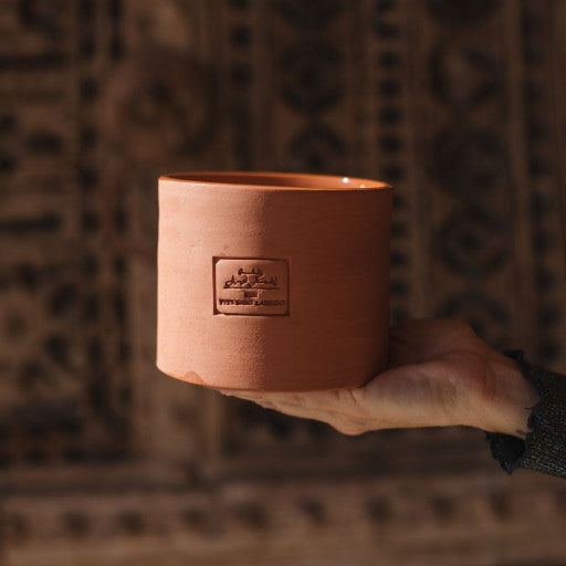 Moyenne bougie dans un contenant en poterie marocaine.