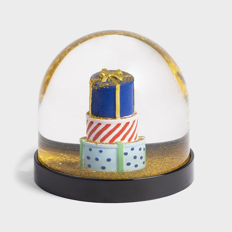 Boule à neige Klevring, avec trois cadeaux ronds empilés, sous des paillettes dorées.