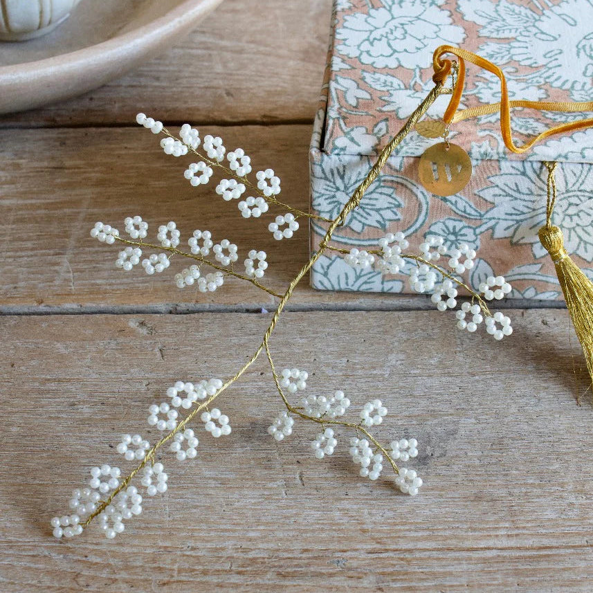 Branche à suspendre en fils dorés torsadés avec fleurs de perles blanches.