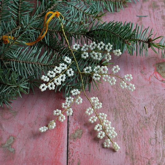 Branche à suspendre en fils dorés torsadés avec fleurs de perles blanches.