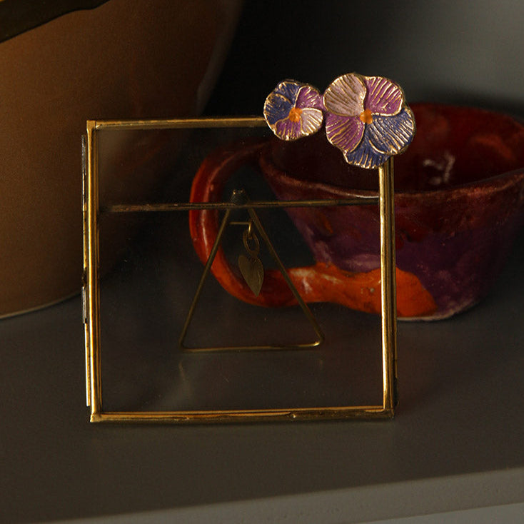 Cadre carré en laiton doré avec fleurs violettes incrustées.