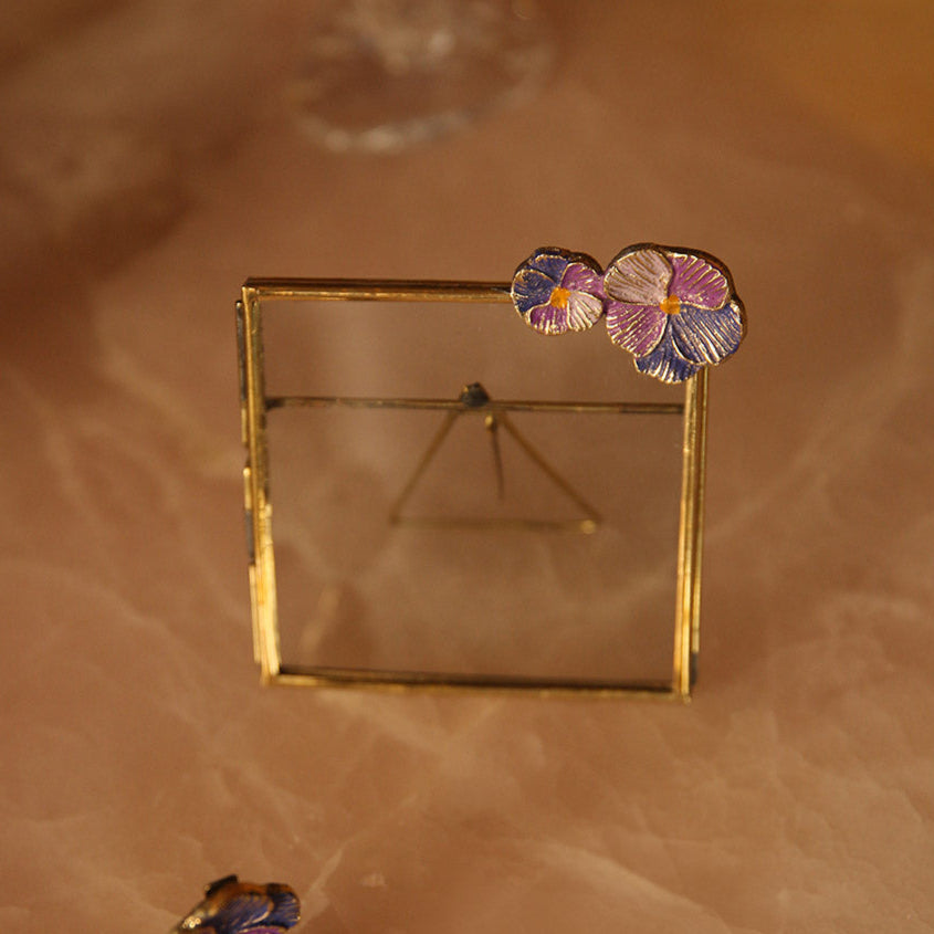 Cadre carré en laiton doré avec fleurs violettes incrustées.