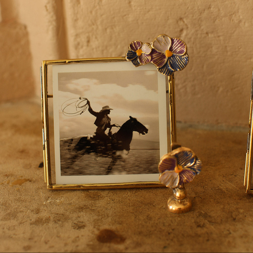 Cadre carré en laiton doré avec fleurs violettes incrustées.