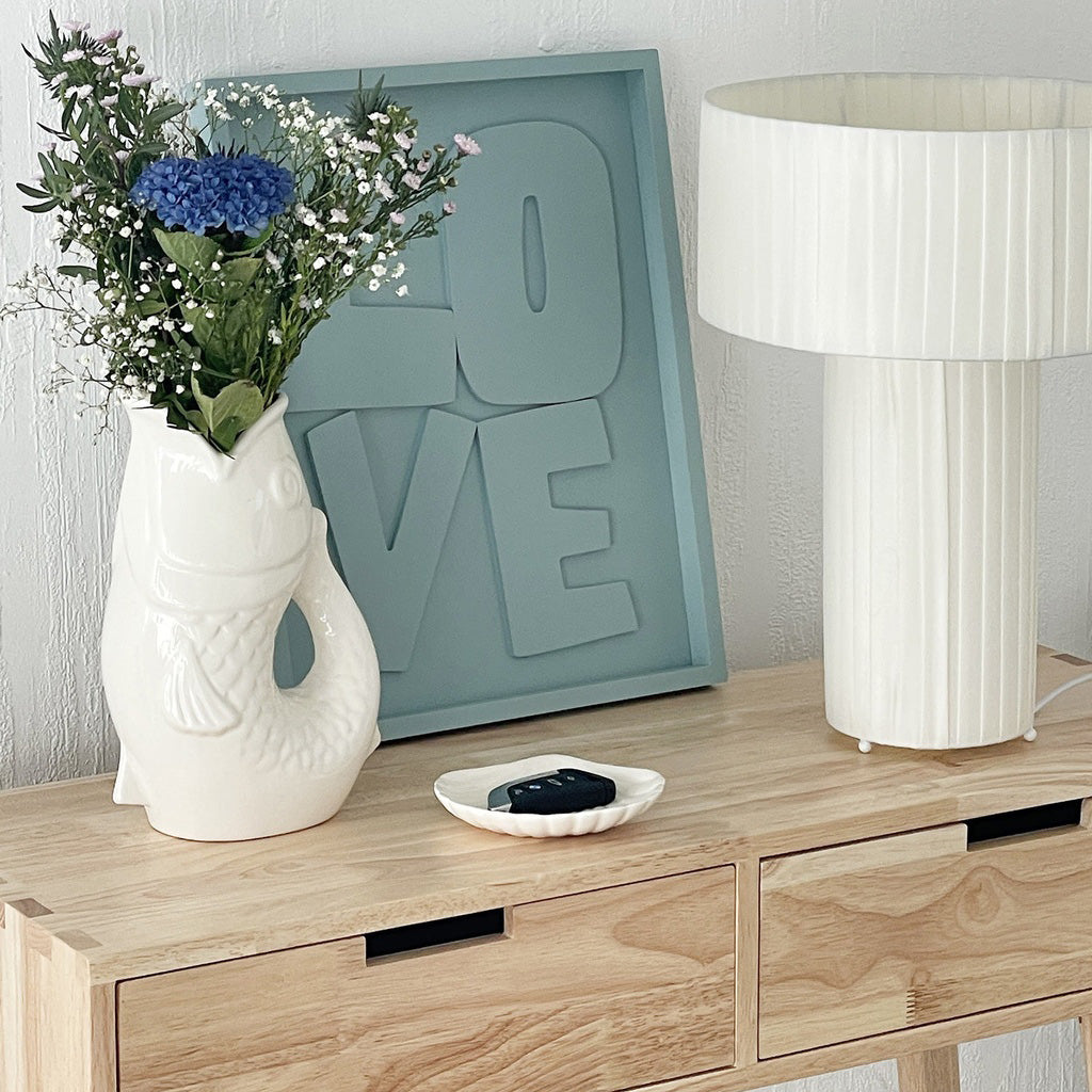 Carafe, vase ou pichet en forme de poisson en céramique blanc dans un décor assorti.