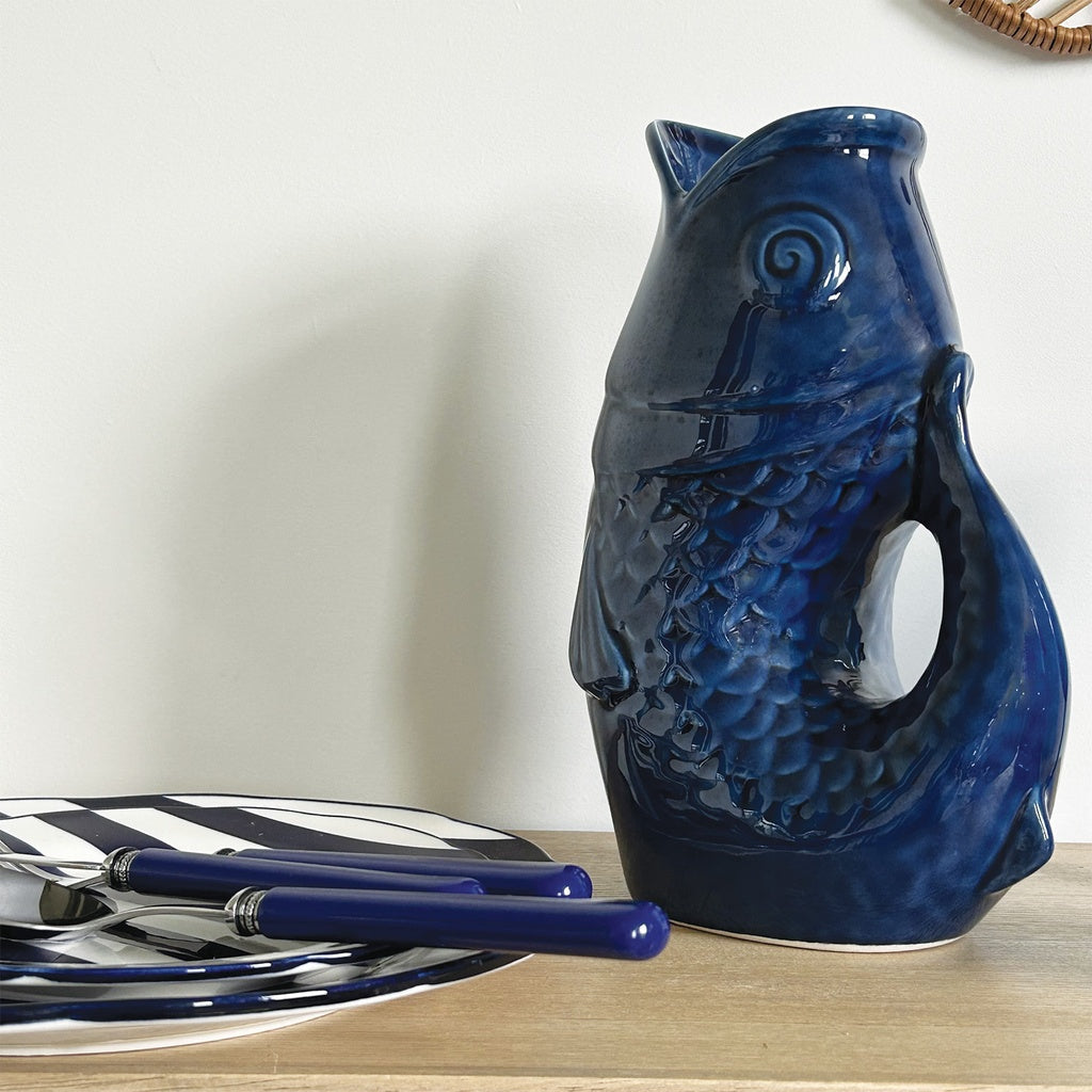 Carafe, vase ou pichet en forme de poisson en céramique bleu foncé dans un décor assorti.