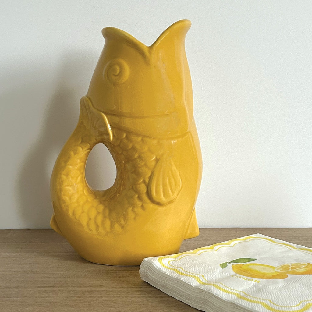 Carafe, vase ou pichet en forme de poisson en céramique jaune safran dans un décor assorti.