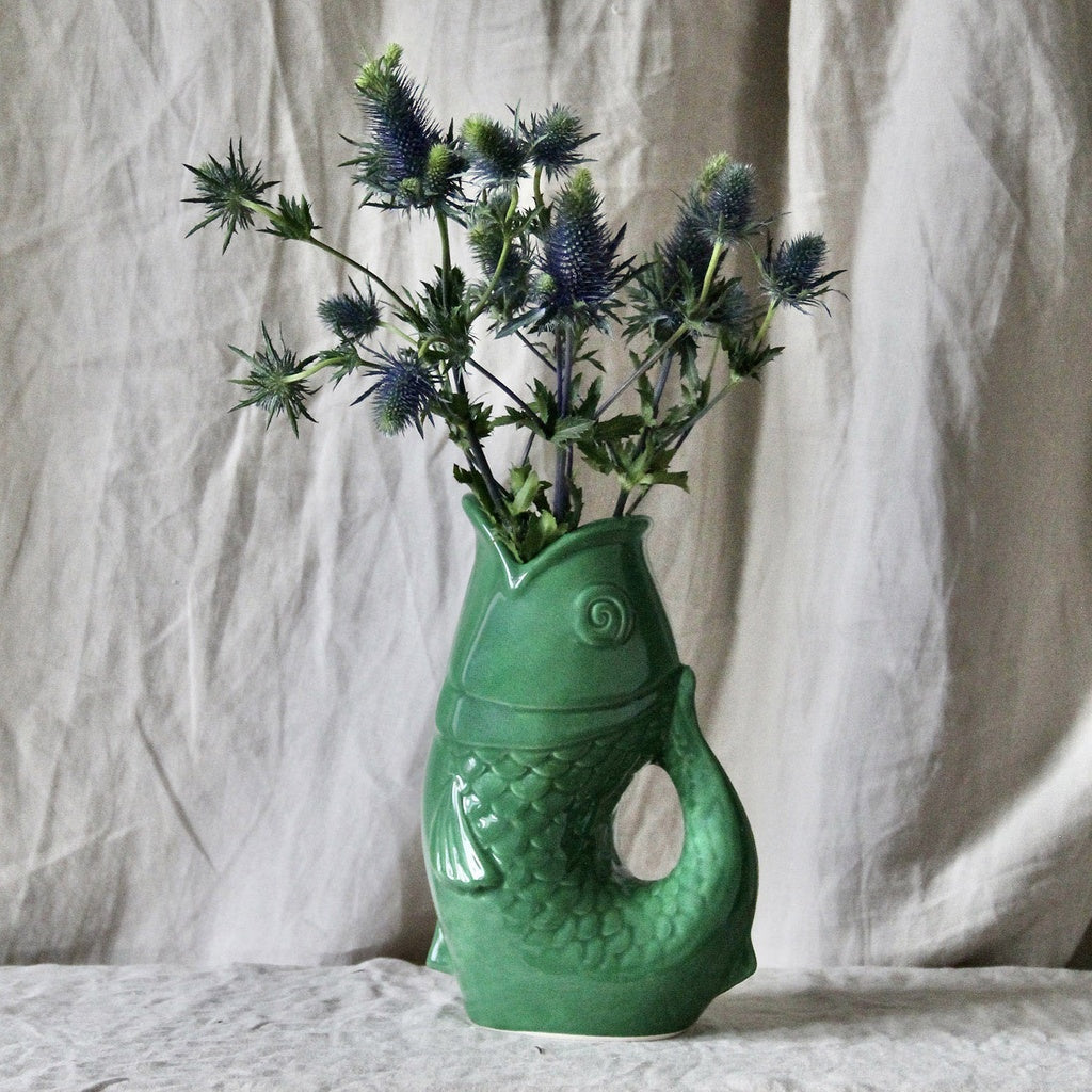 Carafe, vase ou pichet en forme de poisson en céramique vert dans un décor assorti.