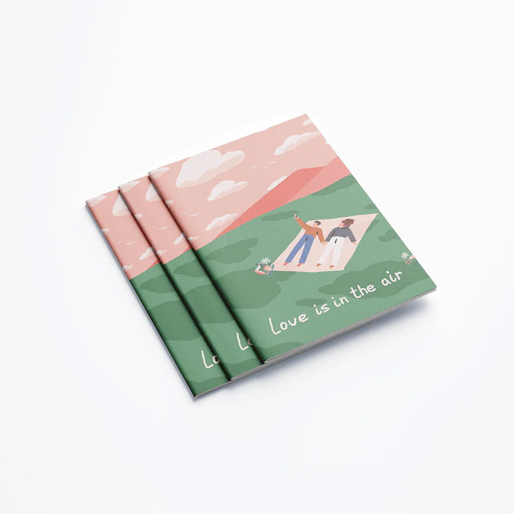 Carnet A6 avec un couple allongé dans l'herbe regardant le ciel en couverture.