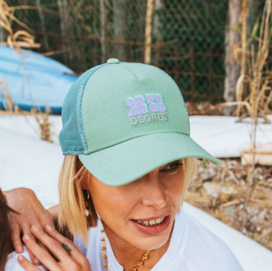 Casquette vert céladon modèle Sunshine avec logo brodé mauve, forme trucker avec filet.