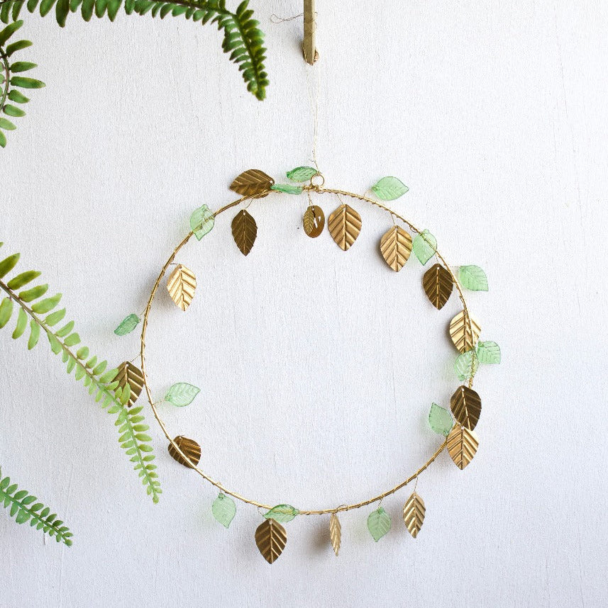 Couronne en fils dorés avec des feuilles dorées et vertes, à poser ou à suspendre en décoration de Noël. 
