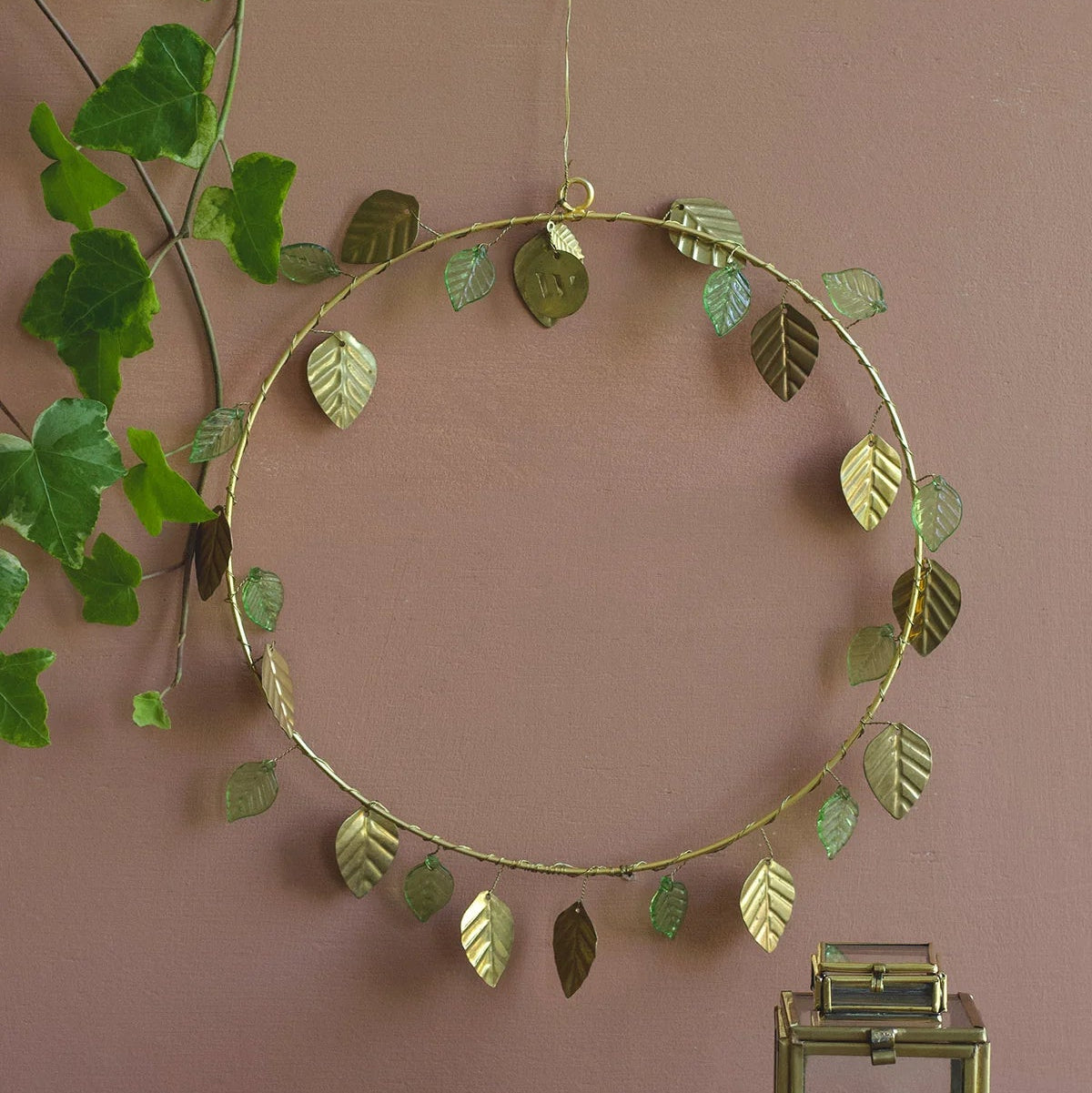 Couronne en fils dorés avec des feuilles dorées et vertes, à poser ou à suspendre en décoration de Noël. 