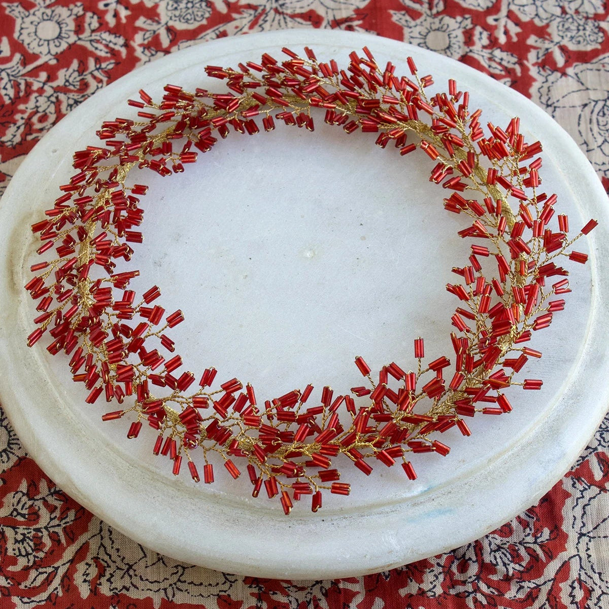 Couronne de perles rouges à suspendre ou à poser comme décoration de Noël.