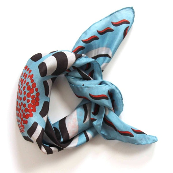 Foulard carré en soie avec dessins de fleurs et feuilles, dans les tons bleu clair, marron, blanc et des touches de rouge. 