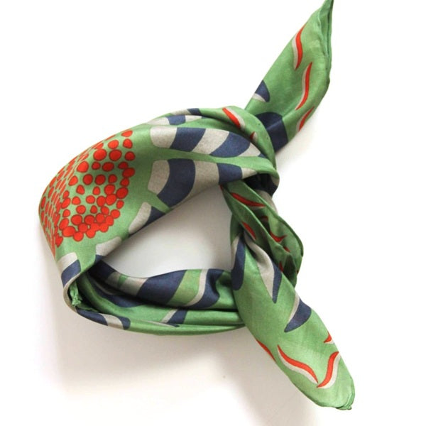 Foulard carré en soie avec dessins de fleurs et feuilles, dans les tons vert, bleu foncé, écru et des touches de orange. 