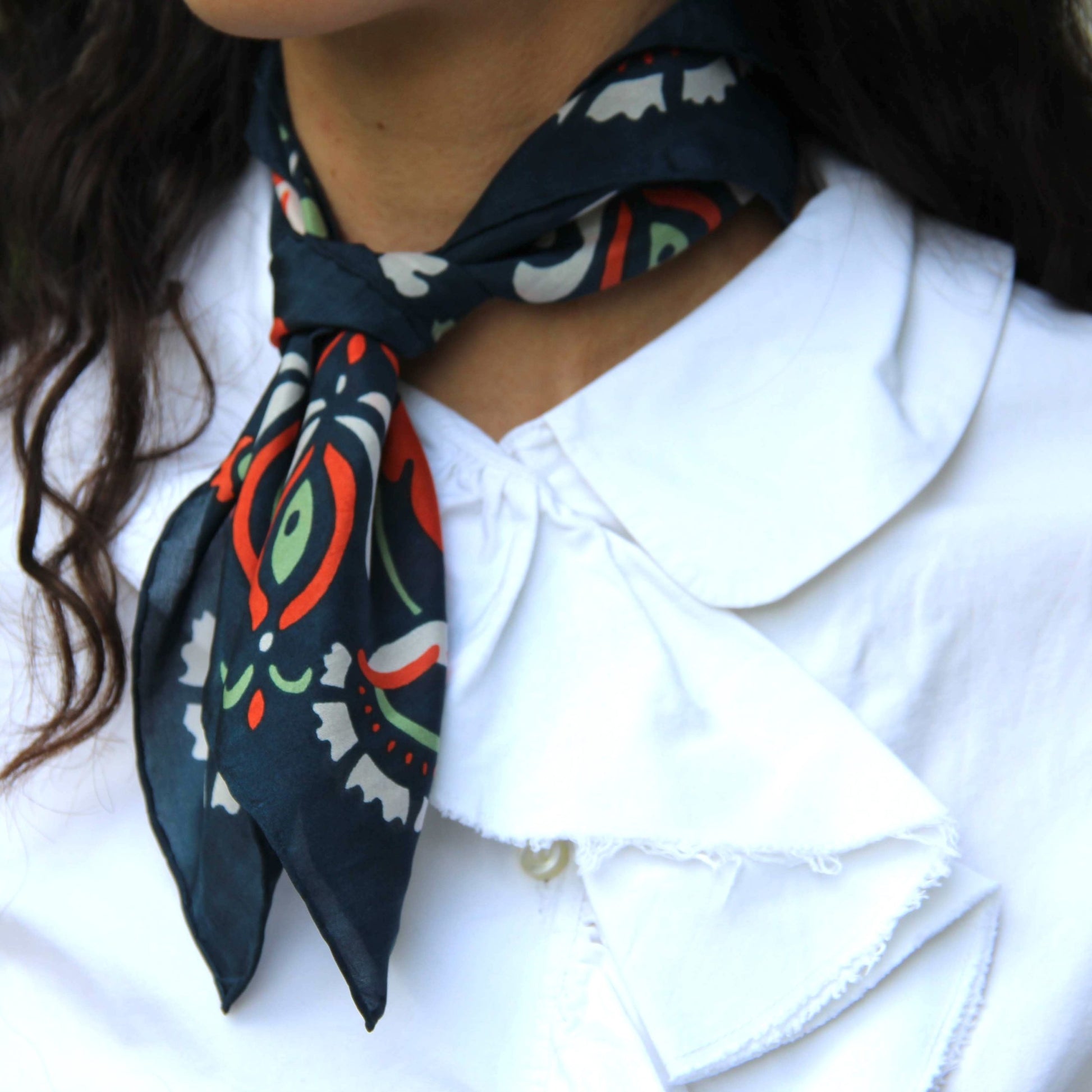 Foulard carré en soie, porté autour du cou, modèle Yulia orange. 