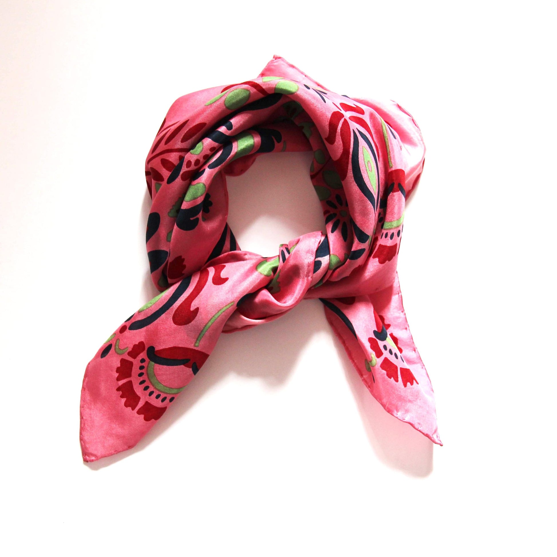 Foulard carré en soie avec motif floral, dans les tons rose, rouge, vert amande et bleu foncé. 
