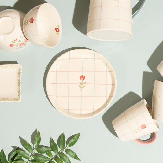 Zoom sur l'assiette à dessert en grès quadrillé avec une fleur centrale. 