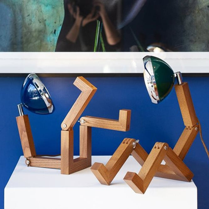Lampe à poser en forme de bonhomme articulé avec un phare à la place de la tête, coloris bleu et vert.