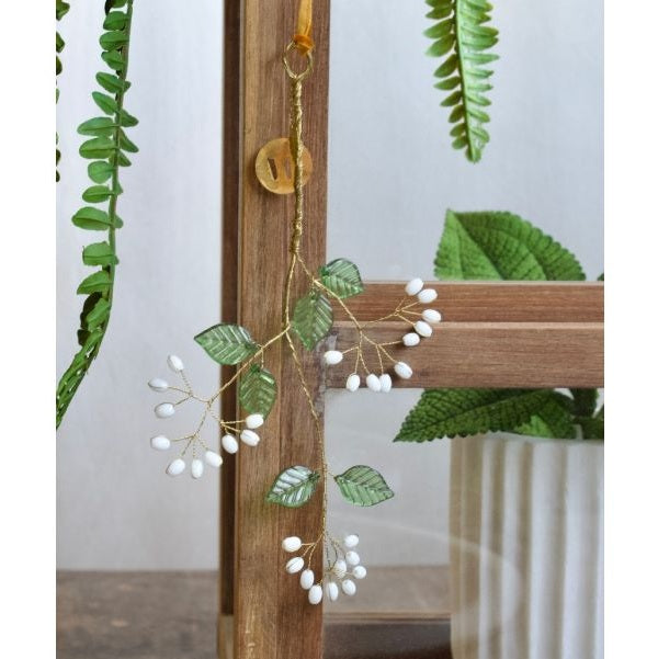 Branche de fleurs blanches en perles et feuilles vertes