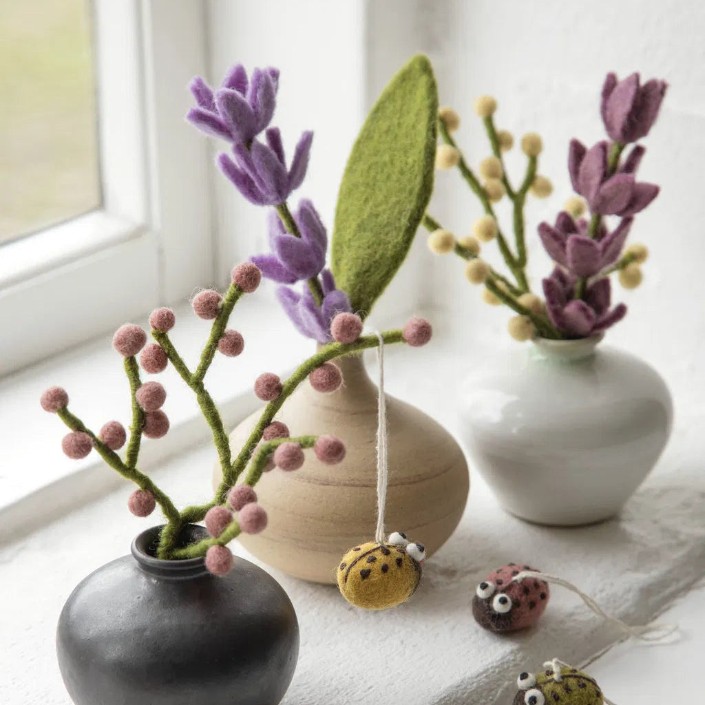 Petits bouquets et branches en laine feutre dans petits vases.