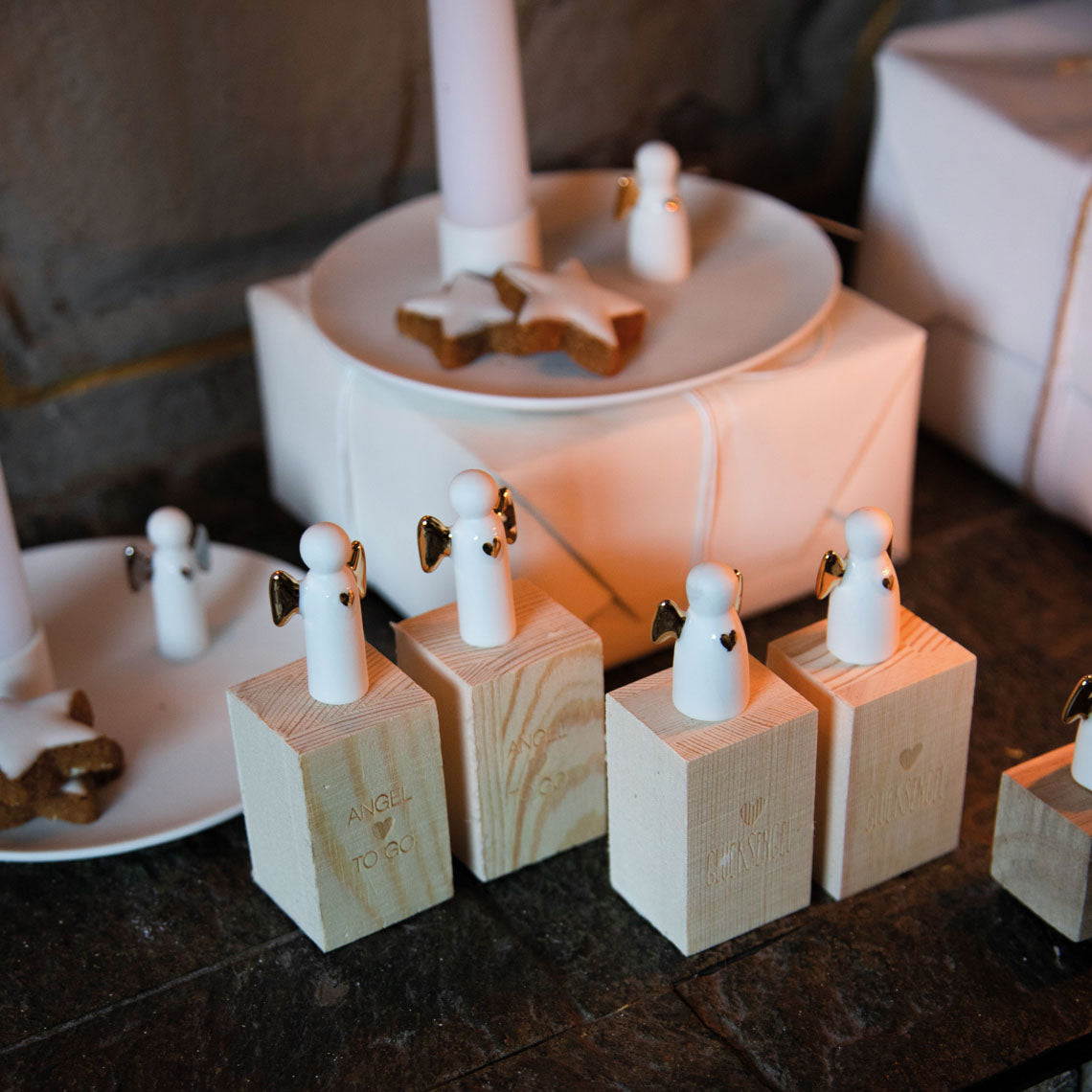 Minis anges en porcelaine blanche avec les ailes dorés posé sur leurs boîtes.