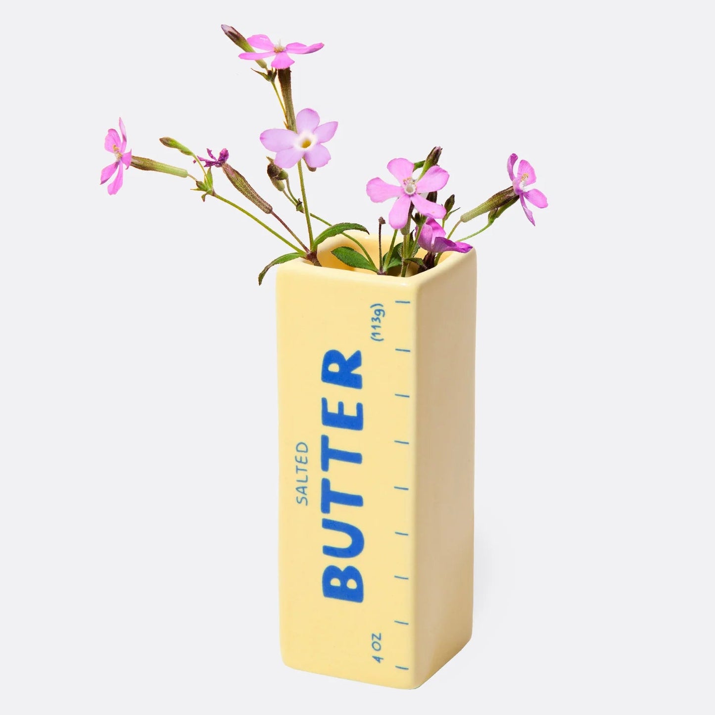 Mini vase en céramique en forme de beurre salé avec petites fleurs dedans.