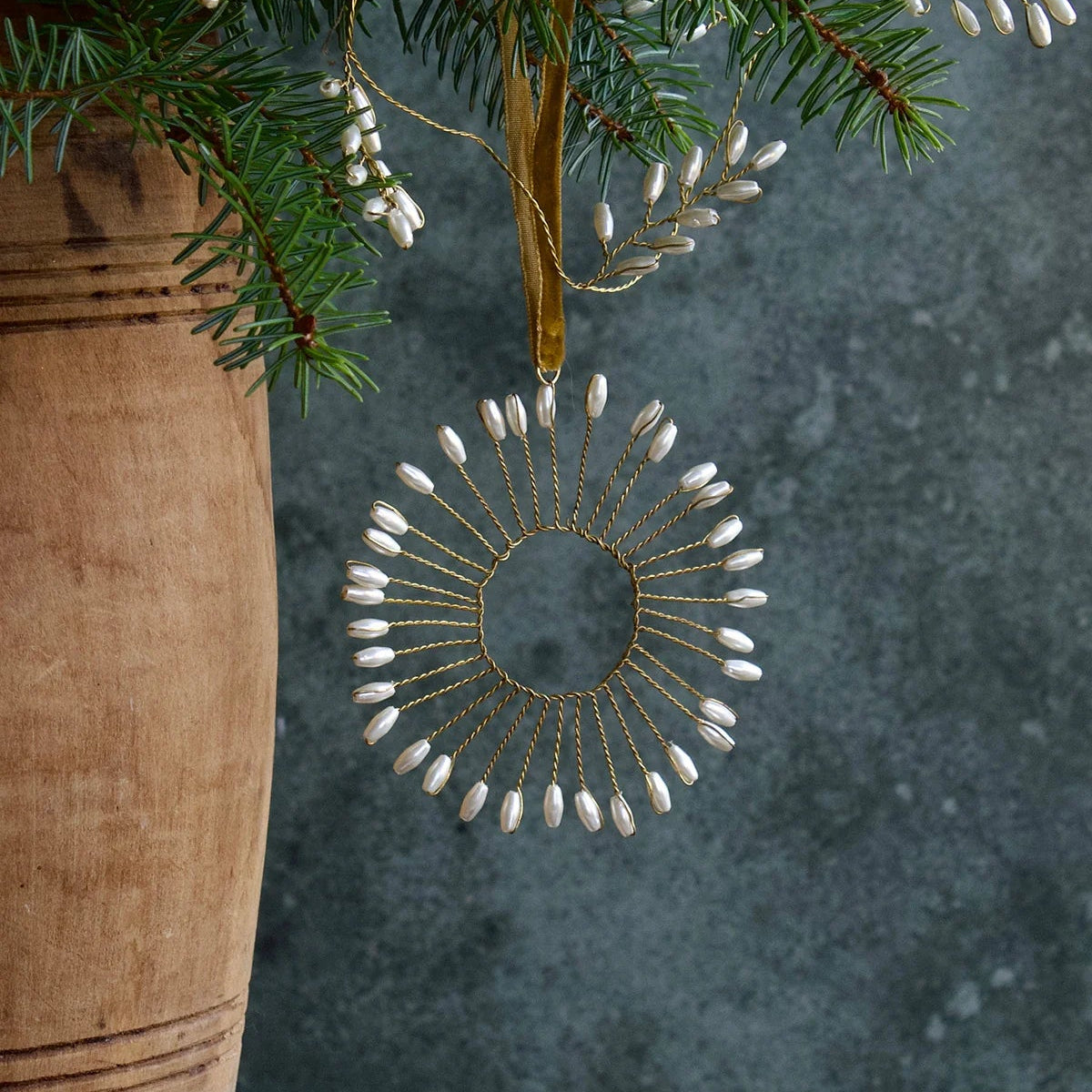 Ornement de Noël à suspendre en forme de soleil étoilé en métal torsadé et extrémités perlées.