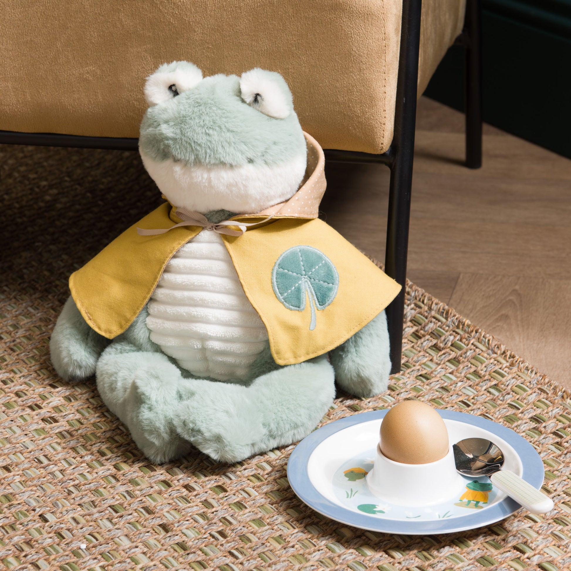 Peluche toute douce en forme de grenouille avec une cape jaune. 