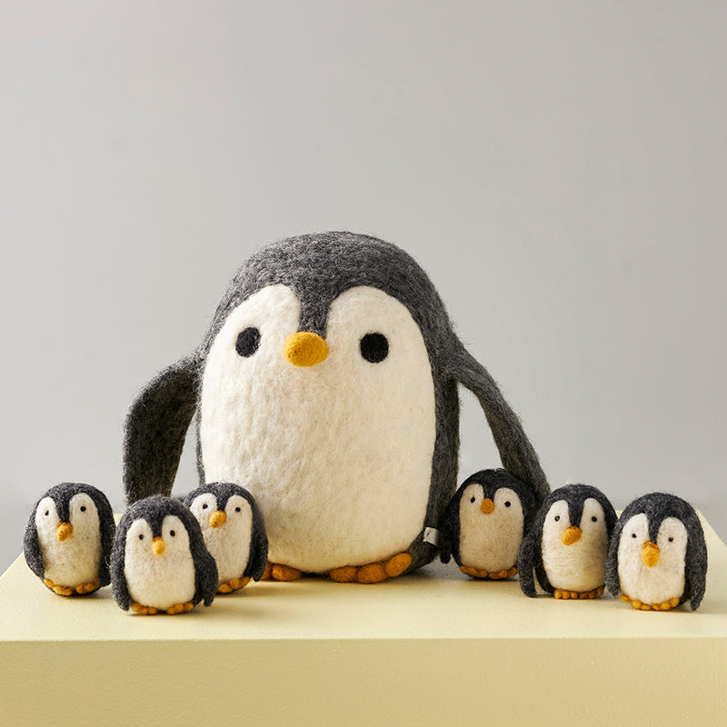 Peluche en laine feutrée en forme de pingouin mignon, de couleurs gris et blanc.