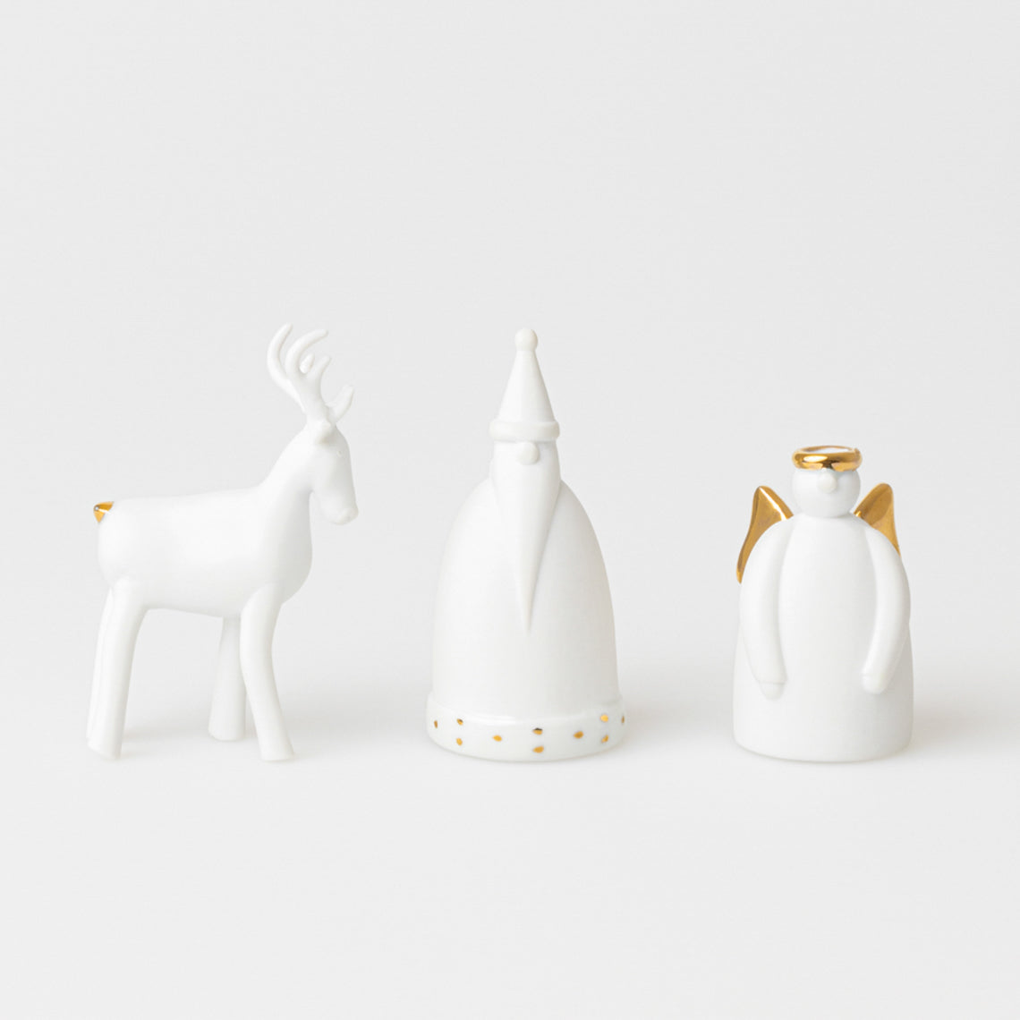 Set de 3 personnages de Noël en porcelaine blanche non émaillée avec des touches de doré : un renne, un père Noël et un ange.