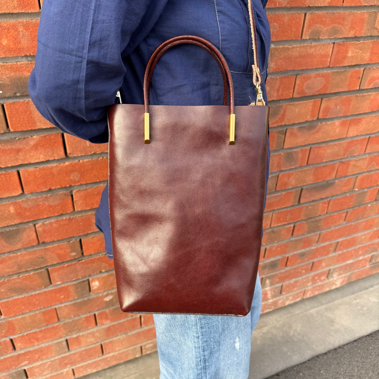 Petit sa seau en cuir, avec anse fixe et bandoulière amovible, coloris marron.