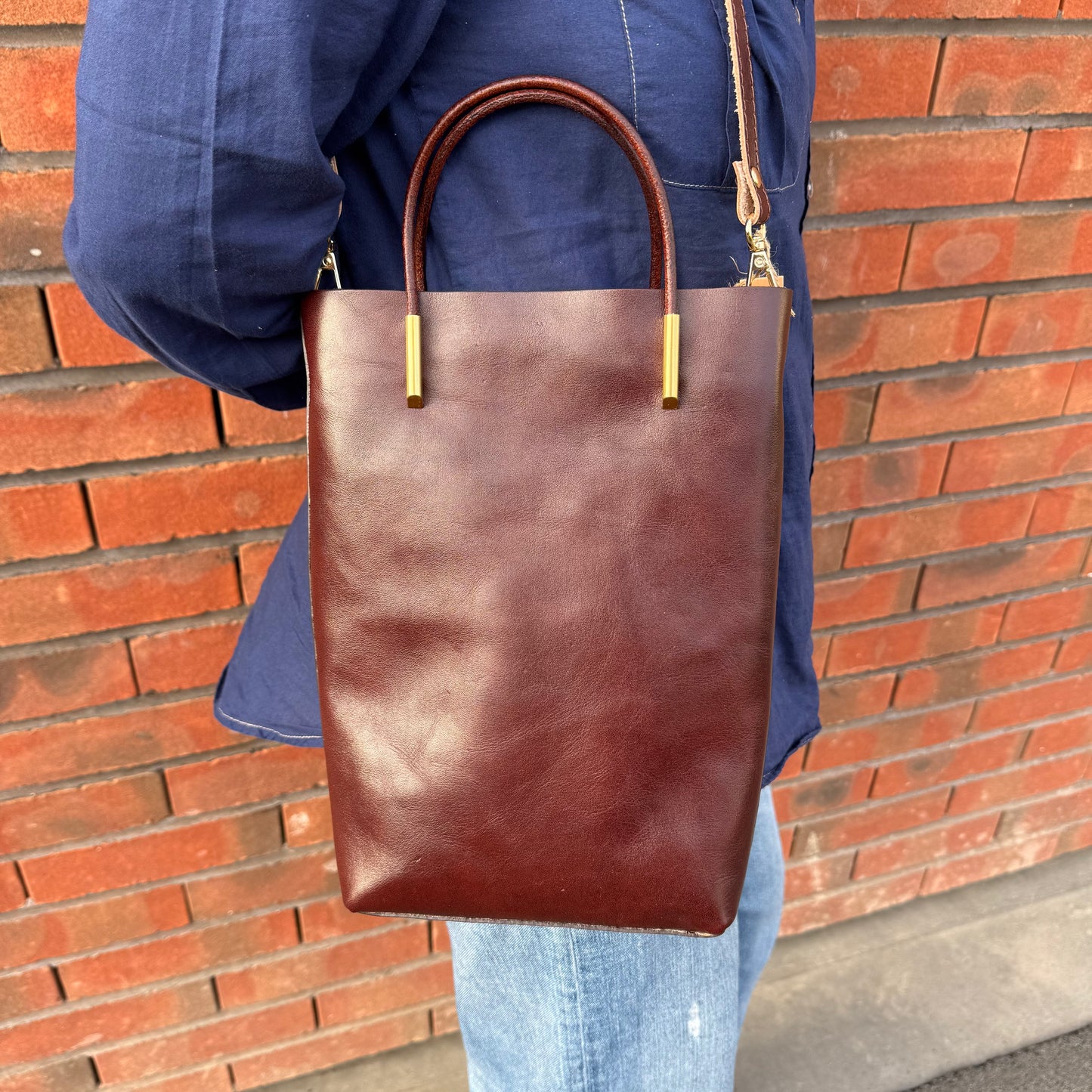 Petit sa seau en cuir, avec anse fixe et bandoulière amovible, coloris marron.