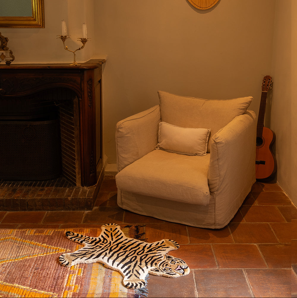 Petit tapis en laine en forme de tigre, au pied d'un fauteuil.