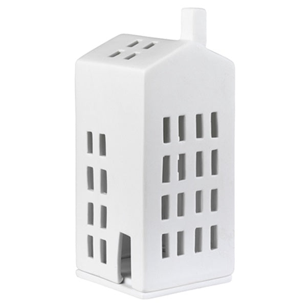 Petit photophore en porcelaine blanche en forme d'immeuble éteint sur fond blanc.