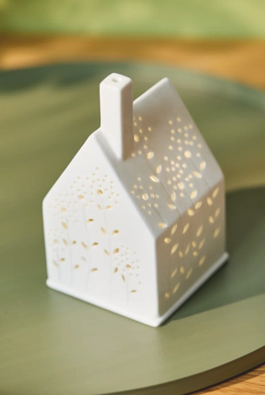 Photophore en porcelaine ajourée en forme de maison, avec façades fleuries.