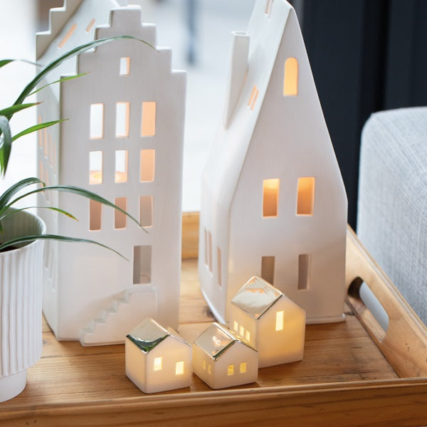 Zoom sur un photophore en porcelaine blanche en forme de maison avec un grand toit pentu.