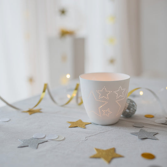 Photophore rond en porcelaine blanche  avec des étoiles découpées.