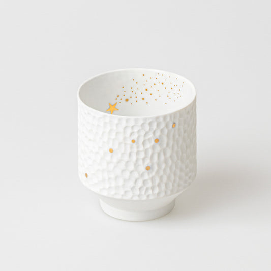 Photophore rond en porcelaine blanche martelée avec une étoile filante et une constellation dorée.