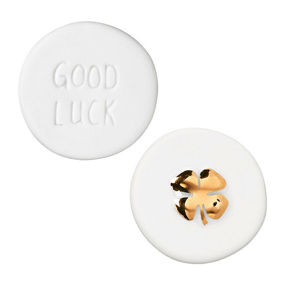 Petite pièce porte-bonheur en porcelaine blanche avec trèfle doré.